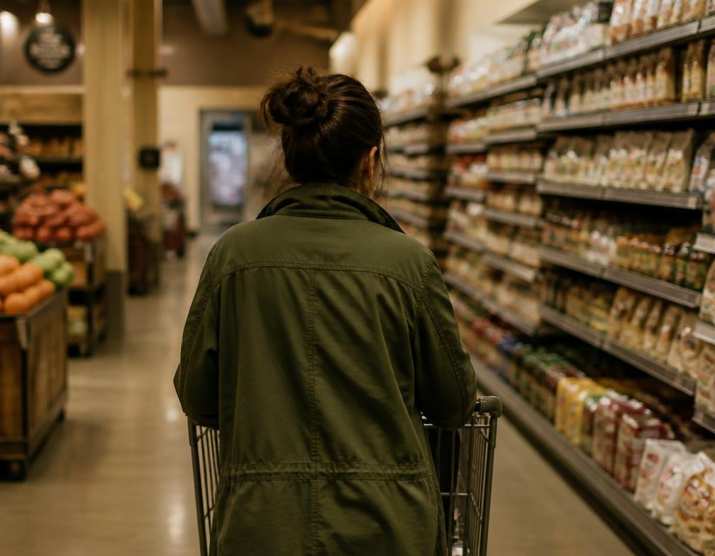 A volunteer handing a bag of groceries to a neighbor at their front door